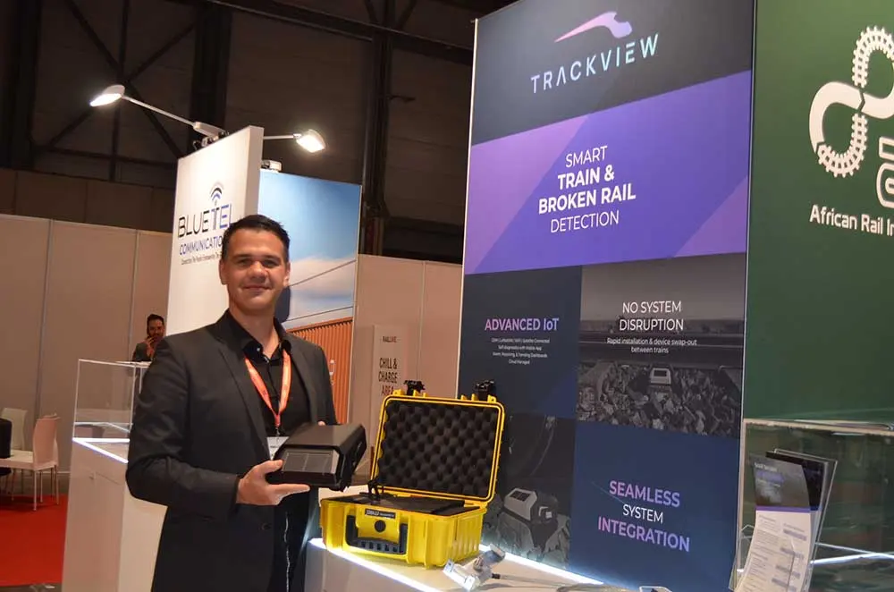 A HisWay Labs representative holding a TrackView device case at the Rail Live 2025 stand in Madrid